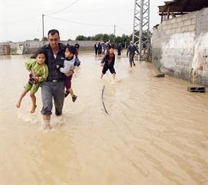 فلسطيني يحاول انقاذ طفليه من الفيضانات التي اجتاحت غزة بعد ان فتحت اسرائيل السدود رويترز