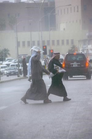 مواطنان يحتميان من المطر الذي هطل على العاصمة امسسعود سالم