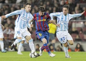 مهاجم برشلونة ليونيل ميسي يمر بالكرة بين لاعبي ملقة قبل ان يسجل هدف الفوز							افپ
﻿