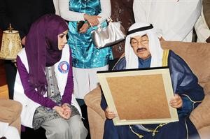 احدى المتطوعات تقدم لوحة للشيخ ناصر المحمد