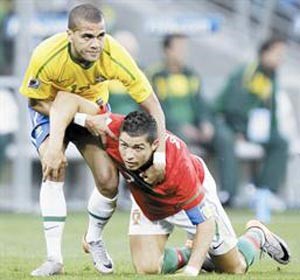 مدافع البرازيل دانيال الفيش يمنع البرتغالي كريستيانو رونالدومن المرور خلال احدى اللعبات المشتركة افپ