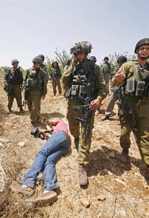 مصور فلسطيني ملقى على الارض بعد ان اعتدت عليه الشرطة الاسرائيلية خلال تغطيته احتجاجات في قرية بيت عمر في الخليل 	افپ﻿
