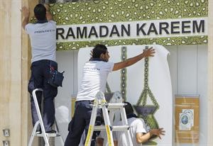 عمال لبنانيون يعلقون لوحات كبيرة ترحيبا بقدوم شهر رمضان المبارك ﻿