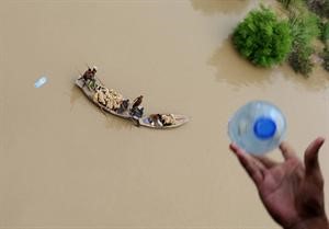 احد رجال الانقاذ الجوي يرمي بزجاجات ماء لباكستانيين حاصرتهم المياه