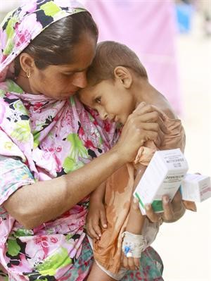 ﻿باكستانية نازحة تحمل طفلها المريض بعد تلقيه العلاج في معسكر نور كوبرااپ﻿