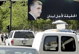 لبنانيون يمرون بجانب صورة كبيرة للرئيس رفيق الحريري كتب عليها الحقيقة لاجل لبنان اپ