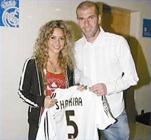 شاكيرا بجوار زيدان وتحمل فانيلة ريال مدريد وعليها اسمها
