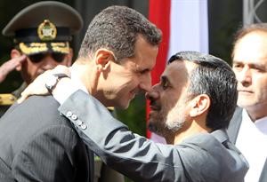 الرئيس الايراني احمدي نجاد معانقا الرئيس السوري دبشار الاسد لدى استقباله في طهران امس	اپ﻿