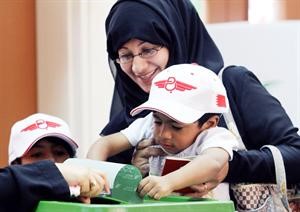 بحرينية ترفع ولدها ليضع الورقة التي ادلت فيها بصوتها في الصندوق الشفاف خلال الانتخابات البحرينية امس	افپ﻿