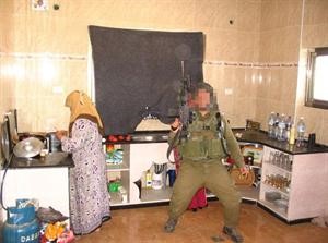 الصورة التي نشرها الموقع الاسرائيلي لجندي اسرائيلي شاهرا سلاحه الى جانب سيدة فلسطينية داخل مطبخ منزلها﻿