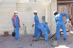 عمال ينزعون الكاشي الذي اصبح لونه اسود بفعل تسرب الغاز