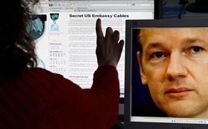 المانية تقرا التسريبات على موقع ويكيليكس فيما تظهر صورة مؤسس الموقع جوليان اسانج على شاشة مجاورةافپ﻿
