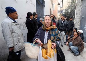 تونسية تحمل الخبز فيما ينتظر اخرون للحصول على حصتهم جراء نقص المواد الغذائية