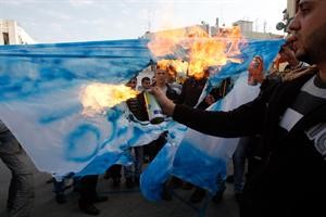 موالون للسلطة الفلسطينية يحرقون علما اسرائيليا مكتوبا عليه كلمة الجزيرة امام مكتب القناة في رام الله امس			رويترز﻿