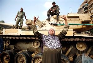سيدة مصرية تعبر عن فرحتها امام احدى دبابات الجيش المصري في ميدان التحرير امس 	رويترز﻿