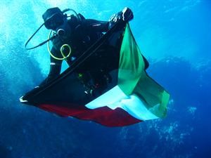 احد اعضاء فريق الغوص يحمل علما للكويت لتثبيته في قاع البحر﻿
