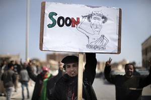ومتظاهر يرفع رسما كاريكاتوريا للزعيم الليبي وهو يحاول الانتحار افپ