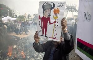 احد المناهضين للزعيم الليبي معمر القذافي يرفع رسما كاريكاتوريا يسخر من لقب ملك الملوك	افپ﻿