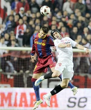 مدافع برشلونة جيرار بيكيه ومهاجم اشبيلية الفارو نيغريدو يتصارعان للحصول على الكرة	افپ﻿