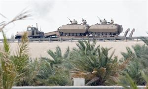 ناقلة مدرعات تحمل عربات عسكرية قرب الحدود السعودية البحرينية في المنامة امس 	رويترز﻿