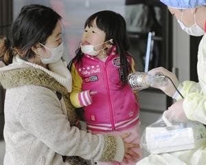 طفلة يابانية تداعب والدتها اثناء فحصها بجهاز كشف الاشعاعات في مدينة فوكوشيما	اپ﻿