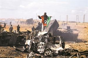 ثوار يرفعون العلم الليبي القديم على حطام 3 اليات من كتائب القذافي دمرتها غارات التحالف امس افپ﻿
