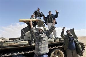 ثوار ليبيون يرفعون علامة النصر ويجمعون قذائف من دبابة تابعة لكتائب القذافي	افپ﻿