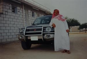 العم محمد غصن الجحدل متكئا على سيارته امام بيته
