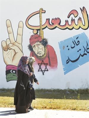 ليبيتان تمران بجانب رسم كاريكاتوري على احد جدران في مدينة بنغازي افپ