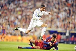 نجم ريال مدريد كريستيانو رونالدو يمر من مدافع برشلونة جيرارد بيكيه افپ