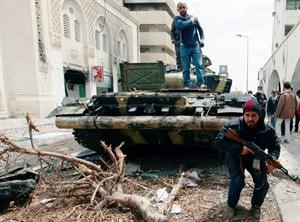 ثوار ليبيون يعتلون دبابة لقوات القذافي ببعد تحطيمها وحرقها في مصراتة امس	رويترز﻿