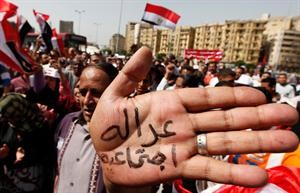 مصريون يتظاهرون في عيد العمال للمطالبة بحقوقهم ويظهر احد المتظاهرين كاتبا على يده عدالة اجتماعية رويترز﻿