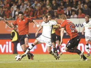 لاعب وسط فالنسيا خواكين سانشيز يحاول المرور من مدافعي اوساسونا سيرجيو فرنانديز والايراني جواد نيكونام افپ