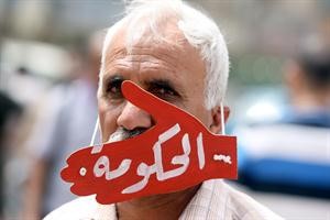 عراقي يرتدي قناعا كتب عليه الحكومة على شك كف يكمم فمه خلال احتجاج مناهض في ساحة التحرير امس 	افپ﻿