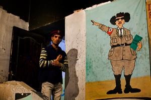 احد الثوار الى جانب رسم كاريكاتوري للعقيد القذافي في بنغازي امس 	اپ﻿