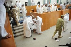 القاعة وقد تناثرت فيها قبعات الشرطة والنواب ويبدو الحربش محاطا بعدد من النواب لتهدئته