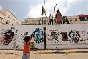 طفل ليبي يصوب مسدسه اللعبة على دمية تمثل الزعيم الليبي معمر القذافي	 رويترز﻿