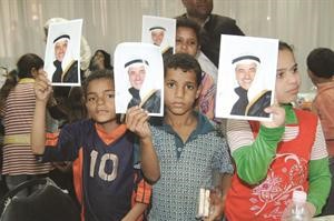 مجموعة من الاطفال يحملون صور الفقيد
