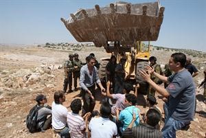 فلسطينيون يحاولون منع جرافة اسرائيلية من تجريف اراضي قرية دير قاديس قرب رام الله	 افپ﻿