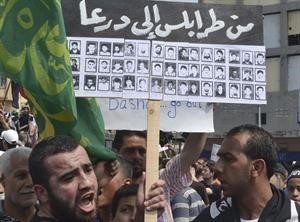 متظاهرون مناهضون للرئيس السوري بشار الاسد يحملون لافتات تضامنية مع درعا في طرابلس امس رويترز