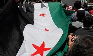 متظاهرون يحملون علما سوريا ضخما قرب سفارة بلادهم في القاهرة امس 