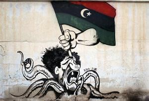 حائط في بنغازي رسم عليه كاريكاتير يصور العقيد القذافي اخطبوطا يضرب بالعلم الليبي