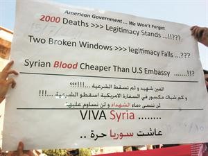 متظاهر في دير الزور يحمل لافتة تنتقد الموقف الاميركي من الاحداث في سورية