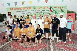 الفائزون في يوم الجري الاولمبي حاملين كؤوسهم