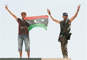 اثنان من الثوار يرفعان علم الثورة على معبر راس جدير ﻿