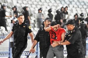 رجال الامن يقتادون احد المشاغبين