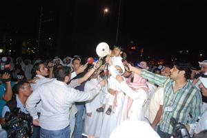 طفل صغير اعتلى كتفي احد الحضور متحدثا بمكبر الصوت
