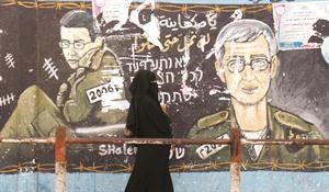 فلسطينية تمر امام جدارية في جباليا مرسوم عليها صورة جلعاد شاليط	افپ﻿