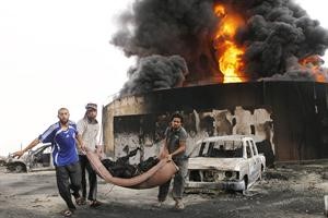 ليبيون يحملون جثة مجهولة من موقع انفجار غامض اصاب احد خزانات الوقود في ضواحي سرت امس رويترز