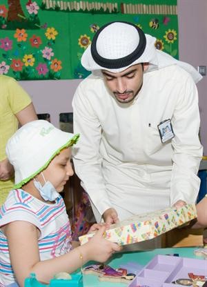 احد متطوعي البنك يقدم هدية لطفلة في المستشفى